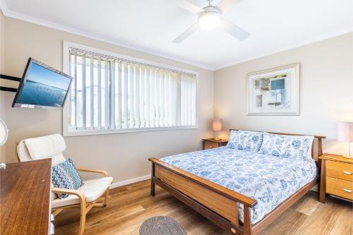 a bedroom with a bed and a desk and a tv at 3 Fingal Court in Fingal Bay
