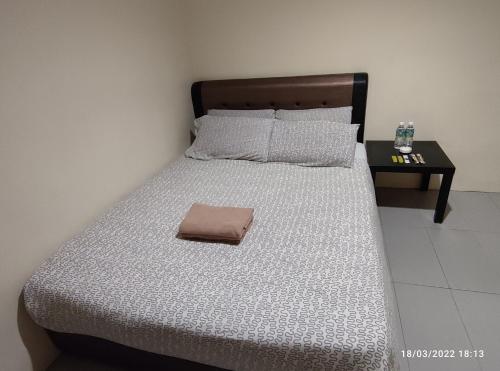 a bed in a bedroom with a nightstand next to it at Fifty Seven Inn in Batu Pahat