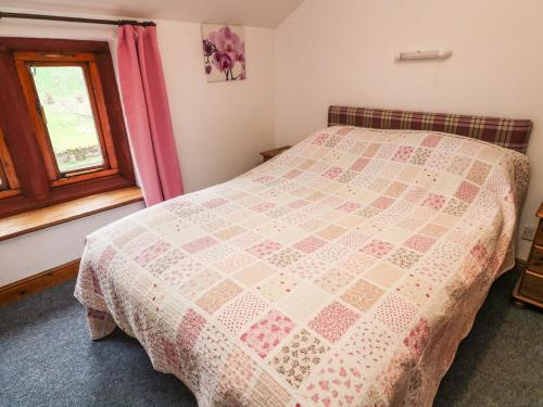 a bedroom with a bed with a quilt on it at Elm Cottage in Warcop