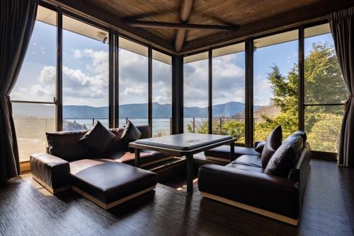 a living room with couches and a table and windows at VILLA HAKONE湖空 in Hakone