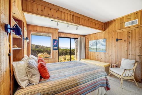 een slaapkamer met een bed, een stoel en een raam bij Starboard Sunset in Bodega Bay