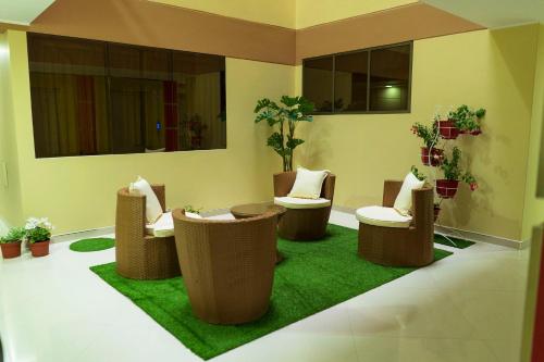a room with chairs and plants on a green rug at R&N SHULLKAS SUITES in Huancayo