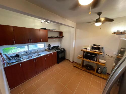a kitchen with brown cabinets and a sink and a microwave at Villa Solara 6 - Luxury 6 Bedroom Villa with Pool, Golf & Lake View in Río Hato