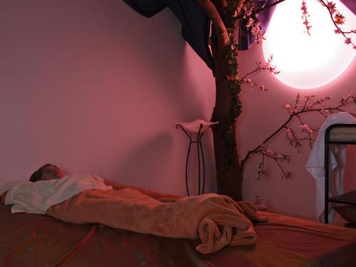 a person laying on a bed next to a tree at Badhotel Restaurant Stauferland in Bad Boll