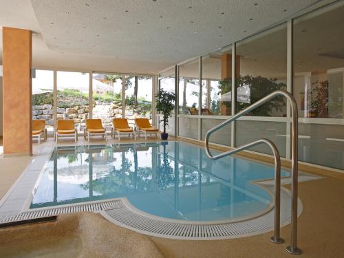 una piscina con sillas naranjas en un edificio en Badhotel Restaurant Stauferland, en Bad Boll