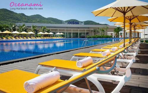 a row of yellow tables and umbrellas next to a swimming pool at Oceanami Resort & Beach Club in Long Hai