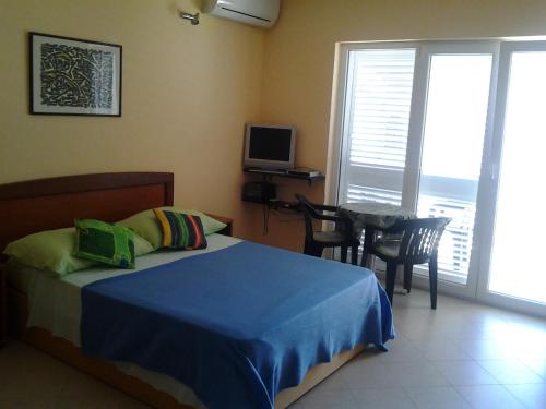 ein Schlafzimmer mit einem Bett und einem Tisch und einem Fernseher in der Unterkunft Apartments Teatina in Brodarica