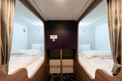 two beds in a room with mirrors at Meimon Taiyo Ferry 2nd sailing from Osaka to Kitakyushu in Osaka
