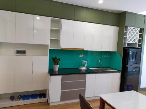 een keuken met witte kasten en een groene muur bij GRAND HYCHARMS Serviced 2BR APARTMENT View Cầu Nhơn Hội in Quy Nhon