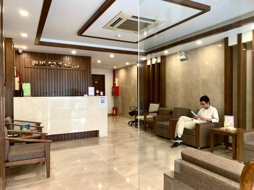 een man op een bank in een lobby bij HOTEL Blue Rose in Hai Phong