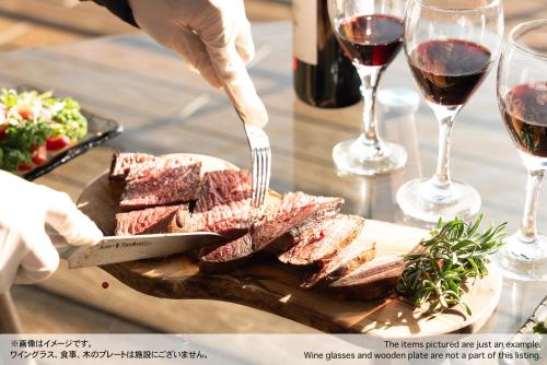 a person cutting meat on a cutting board with a knife and fork at VILLA HAKONE湖空 in Hakone