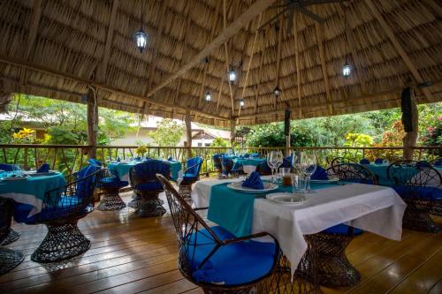 a restaurant with blue tables and chairs on a wooden floor at Mariposa Belize Beach Resort in Placencia Village