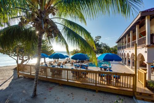 a beach with chairs and umbrellas on the beach at Mariposa Belize Beach Resort in Placencia Village