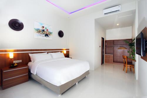 1 dormitorio con 1 cama blanca grande y TV en The Jumbo Homestay, en Kuta Lombok