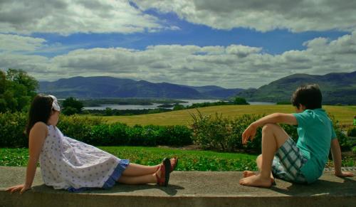 two people sitting on a bench in front of a stone wall at Aghadoe Heights Hotel & Spa in Killarney