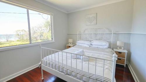 a white bedroom with a bed and a window at Abbey Beachviews with WiFi in Vasse