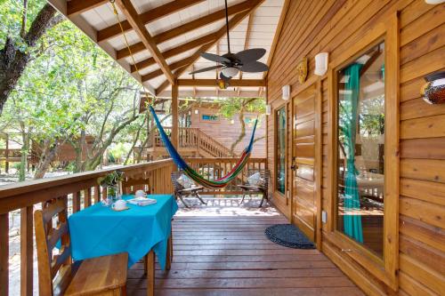 a porch with a blue table and a hammock at Mariposa Belize Beach Resort in Placencia Village