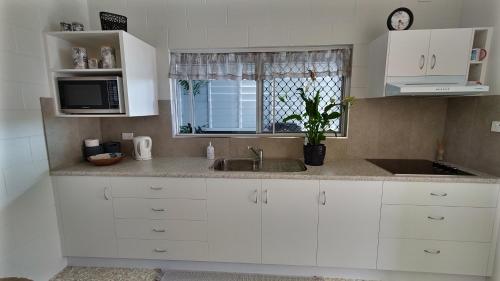 a kitchen with white cabinets and a sink and a window at Hidden Gem Holiday Let in South Mission Beach