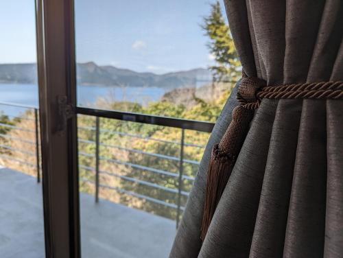 a window with a view of the ocean from a balcony at VILLA HAKONE湖空 in Hakone