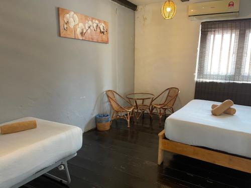 a room with two beds and a table and chairs at Layang Layang Guest House Melaka in Melaka