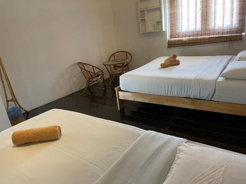 a room with two beds and two chairs and a table at Layang Layang Guest House Melaka in Melaka