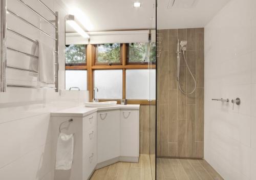 a white bathroom with a shower and a sink at Coolong in Dinner Plain