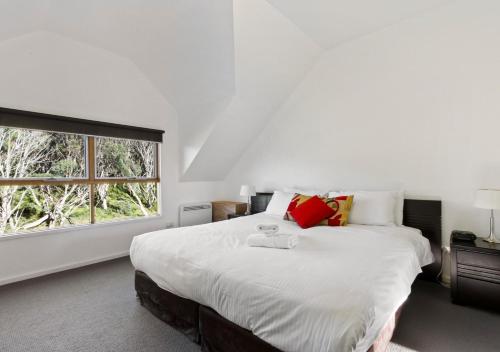 a white bedroom with a large bed and a window at Crooked 2 in Dinner Plain