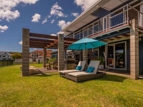 a patio with two lounge chairs and an umbrella at Hosts on the Coast Whitianga Bliss in Whitianga