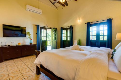 a bedroom with a large white bed and windows at Mariposa Belize Beach Resort in Placencia Village