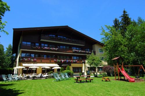 un gran edificio con un parque infantil delante de él en Parkhotel Kirchberg, en Kirchberg in Tirol