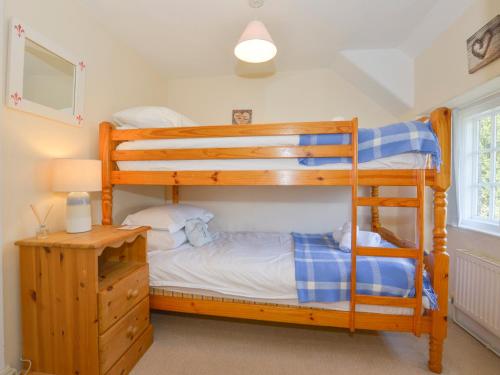 a bedroom with two bunk beds and a desk at Yew Tree Cottage in Dartmouth