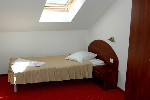 a small bedroom with a bed and a mirror at Hotel Iris in Arad