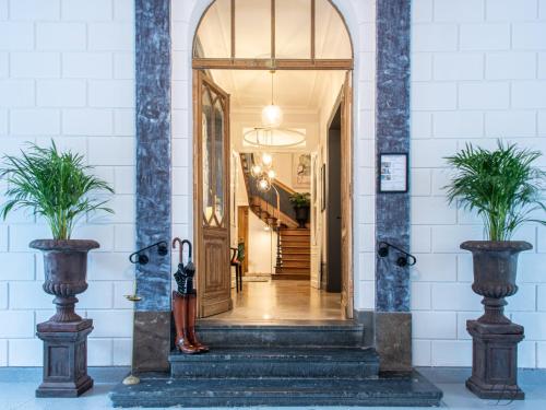 a hallway with an open door with two potted plants at La Demeure Numéro 5 in Cambrai