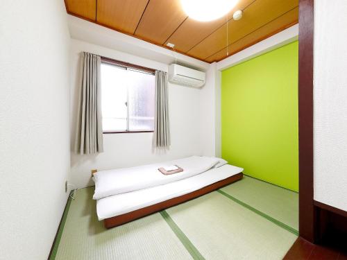 Business Hotel Taiyo في أوساكا: غرفة نوم بجدران خضراء وبيضاء وسرير