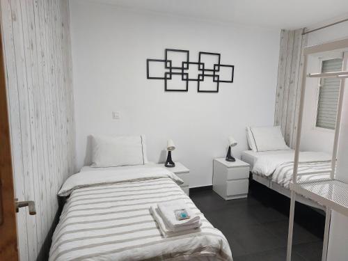 Habitación blanca con 2 camas y espejo. en Apartamento Turismo Badajoz, en Badajoz