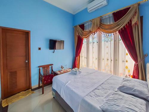 een blauwe slaapkamer met een bed en een raam bij Pakde air cafe and homestay Grabag Magelang Mitra RedDoorz in Bedono