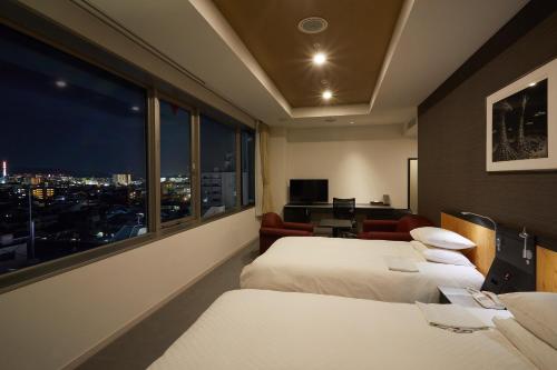 Rhino Hotel Kyoto في كيوتو: غرفة فندقية بسريرين ونافذة كبيرة