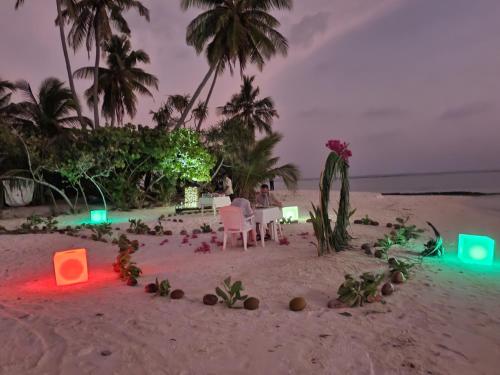 a couple sitting at a table on the beach at Island Life Maldives Retreat & Spa in Magoodhoo