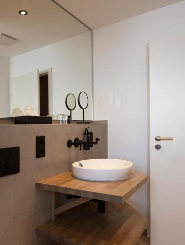 a bathroom with a white sink and a mirror at Hofgut Wißberg - Das Weinberghotel in Sankt Johann