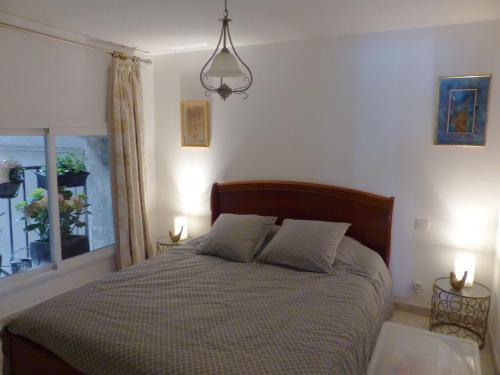 een slaapkamer met een bed met 2 lampen en een raam bij L'antre sol in Sète