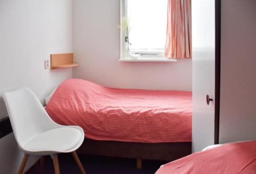 um pequeno quarto com uma cama e uma cadeira branca em Wyn 72 em Hollum