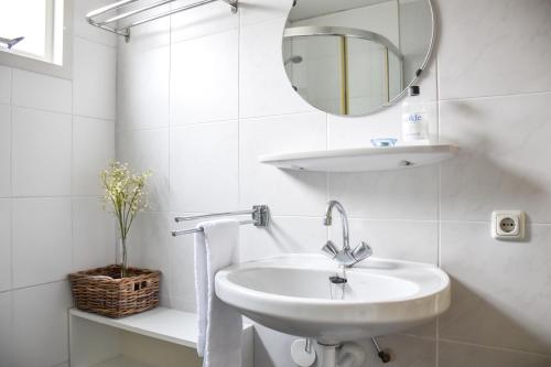 een witte badkamer met een wastafel en een spiegel bij Wyn 72 in Hollum