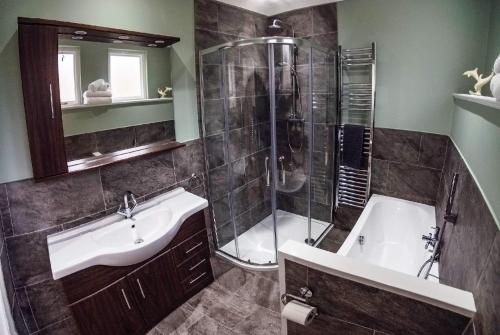 een badkamer met een douche, een wastafel en een bad bij Owls Nest in Edinbain