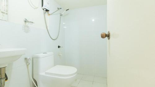 a white bathroom with a shower and a toilet at Skyleigh Apartelle by RedDoorz in Iloilo City