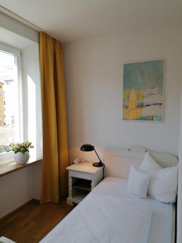 a bedroom with a white bed and a window at Hotel Wendelstein in Rosenheim