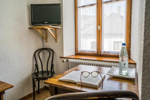 a table with a book and a bottle of water and glasses at Hôtel Au Vieux Moulin in Lapoutroie