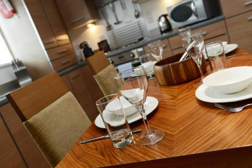 a wooden table with glasses and plates on it at PREMIER SUITES Newcastle in Newcastle upon Tyne
