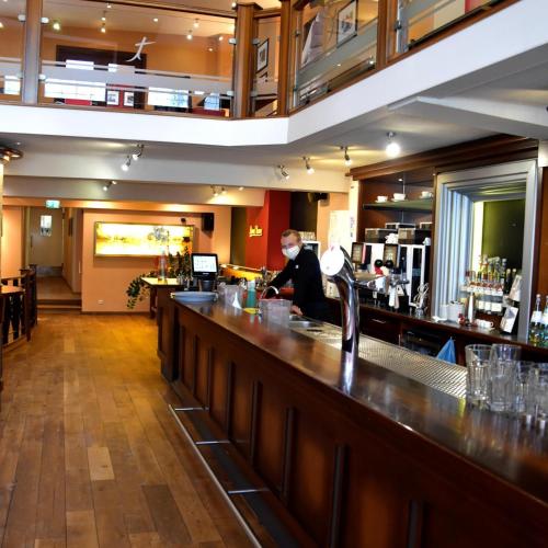 a man standing at a bar in a restaurant at Hotel zur Börse in Hameln