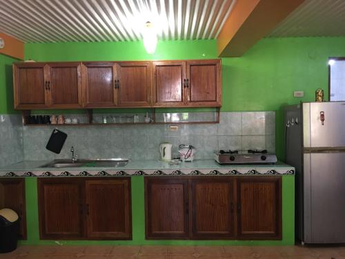 una cocina con armarios de madera y una pared verde en Swahili Apartelle en Boracay