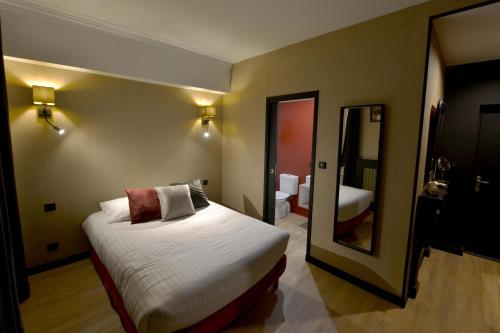 a hotel room with a bed and a mirror at Hôtel Le Tiburon in Cherbourg en Cotentin